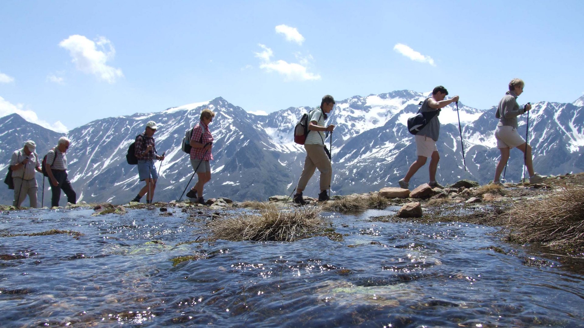 Wandern in den Ötztaler Alpen: von Ihrem Hotel in die Berge Gruppe von Wanderern mit Stöcken am Berg mit Schneegipfeln und klarem Wasser