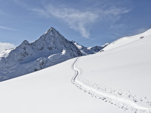 Passez de fantastiques vacances d’hiver au Tyrol. Sommet de montagne enneigé avec traces dans la neige fraîche