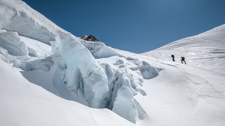 Des impressions de notre hôtel alpin à Vent ! Deux randonneurs montent une montagne enneigée avec formations de glace sous un ciel bleu