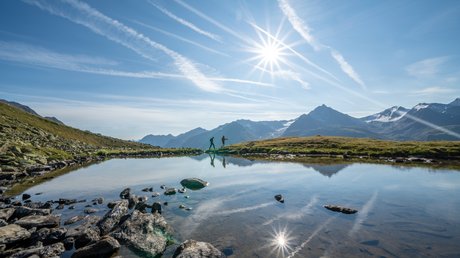 Des impressions de notre hôtel alpin à Vent ! Randonneurs au bord d'un lac de montagne sous un ciel ensoleillé