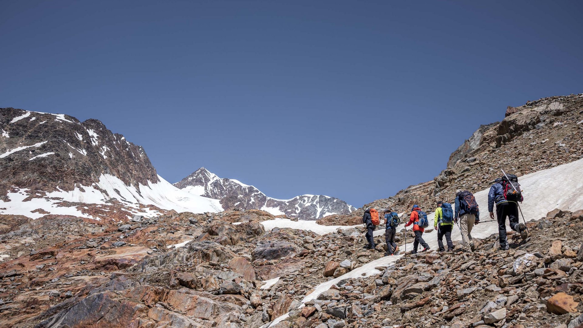 Sur le Similaun et la Wildspitze de notre hôtel à Vent Groupe de randonneurs gravissant un terrain rocheux dans les montagnes enneigées
