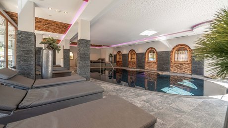 Des impressions de notre hôtel alpin à Vent ! Piscine intérieure moderne avec chaises longues et décor en bois