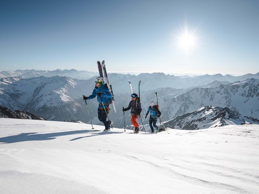 Skitouren rund um Vent: direkt von Ihrem Hotel in die Berge Drei Skifahrer steigen bei Sonnenschein in verschneiten Bergen auf