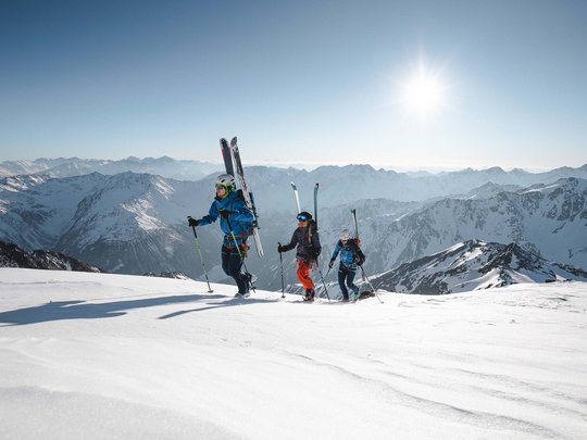 Skitouren rund um Vent: direkt von Ihrem Hotel in die Berge Drei Skifahrer steigen bei Sonnenschein in verschneiten Bergen auf