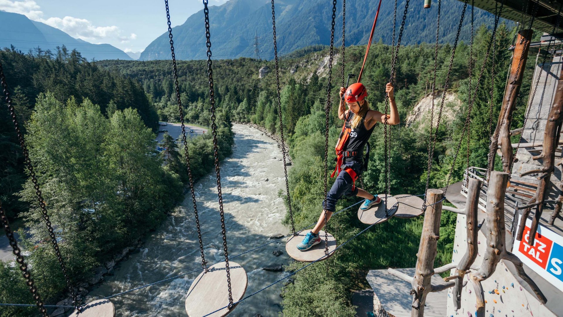 Natur- und Alpinhotel Post: Sehenswürdigkeiten im Ötztal Frau klettert gesichert über schwebende Podeste in Kletterpark über Fluss