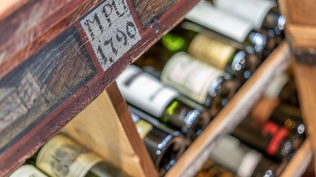 Impressionen aus unserem Natur- und Alpinhotel in Vent Weinflaschen in einem alten, holzbeschrifteten Weinregal