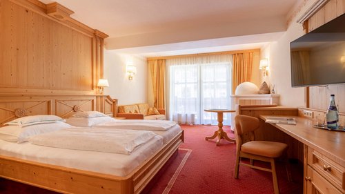 Neues und Wissenswertes aus Vent Hell eingerichtetes Hotelzimmer mit zwei Betten, Sofa, Schreibtisch und Balkon