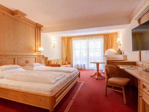 Das Wellnesshotel im Ötztal für Ruhesuchende Hell eingerichtetes Hotelzimmer mit zwei Betten, Sofa, Schreibtisch und Balkon