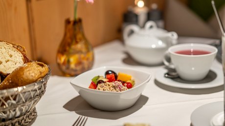 Impressionen aus unserem Natur- und Alpinhotel in Vent Frühstückstisch mit Müsli, Obst, Brot und Tee in weißem Geschirr
