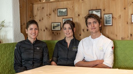 Des impressions de notre hôtel alpin à Vent ! Trois professionnels de la restauration souriants en tenue assis à une table devant un mur en bois