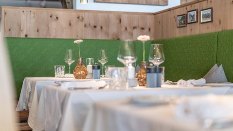 Des impressions de notre hôtel alpin à Vent ! Tables dressées avec nappes blanches et banquettes vertes dans un restaurant