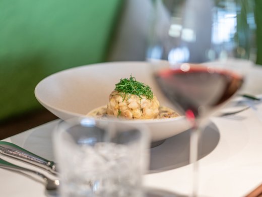 Lieu de rêve Vent : notre hôtel dans l’Ötztal Boulette de pain aux herbes fraîches dans un bol blanc, verre de vin rouge et couverts