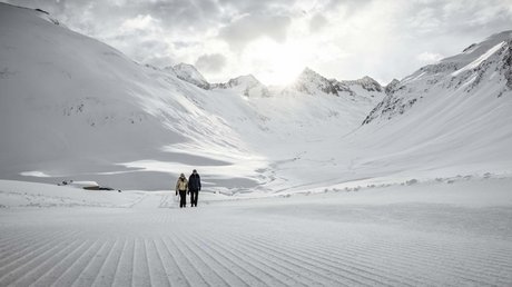 Des impressions de notre hôtel alpin à Vent ! Un couple marche sur une piste fraîchement damée dans les montagnes enneigées