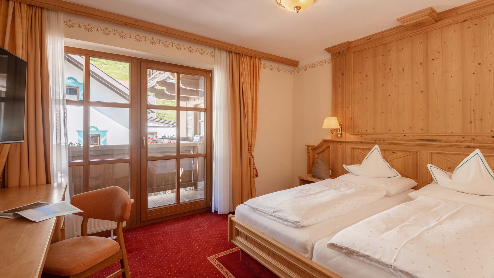 Das Wellnesshotel im Ötztal für Ruhesuchende Gemütliches Doppelzimmer mit Holzmöbeln und Balkon in warmen Farben