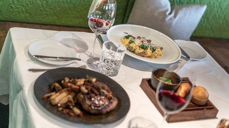 Des impressions de notre hôtel alpin à Vent ! Table dressée avec pâtes, steak, vin rouge et pain sur une nappe blanche