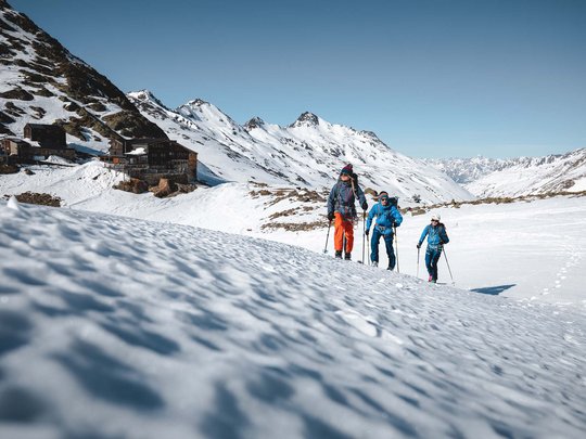 Skitouren rund um Vent: direkt von Ihrem Hotel in die Berge Drei Wanderer in Winterkleidung wandern durch schneebedeckte Berge bei klarem Himmel