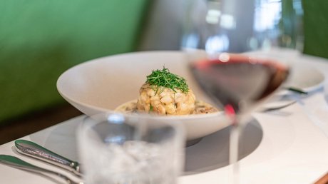 Des impressions de notre hôtel alpin à Vent ! Plat servi avec herbes dans une assiette blanche, verre de vin rouge au premier plan