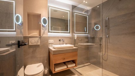 Des impressions de notre hôtel alpin à Vent ! Salle de bain moderne avec miroir éclairé, lavabo, toilettes et douche à l'italienne