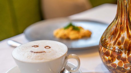 Des impressions de notre hôtel alpin à Vent ! Tasse de cappuccino avec un visage souriant en mousse de lait sur une table