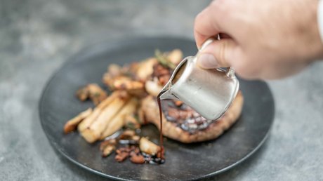 Des impressions de notre hôtel alpin à Vent ! Main verse une sauce sur une viande grillée avec légumes sur assiette noire
