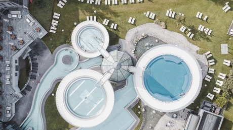 Des impressions de notre hôtel alpin à Vent ! Vue aérienne d'une piscine moderne avec bassins ronds et chaises longues sur pelouse