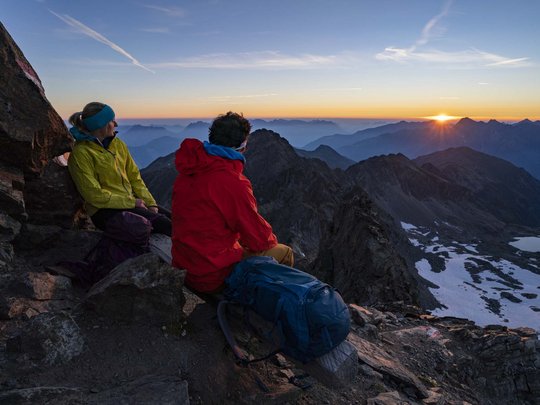 Sur le Similaun et la Wildspitze de notre hôtel à Vent Deux randonneurs assis sur des rochers regardant le coucher de soleil sur les montagnes