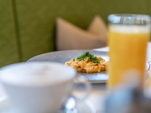 Des plaisirs naturels dans notre restaurant à Vent Œufs brouillés aux ciboulettes sur assiette avec jus d'orange et café flous au premier plan