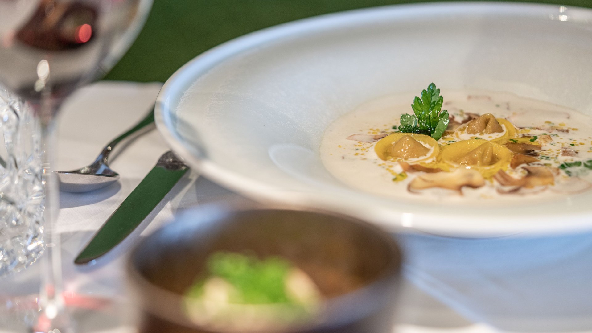 Des plaisirs naturels dans notre restaurant à Vent Assiette de tortellinis en sauce crémeuse aux champignons avec verre de vin rouge