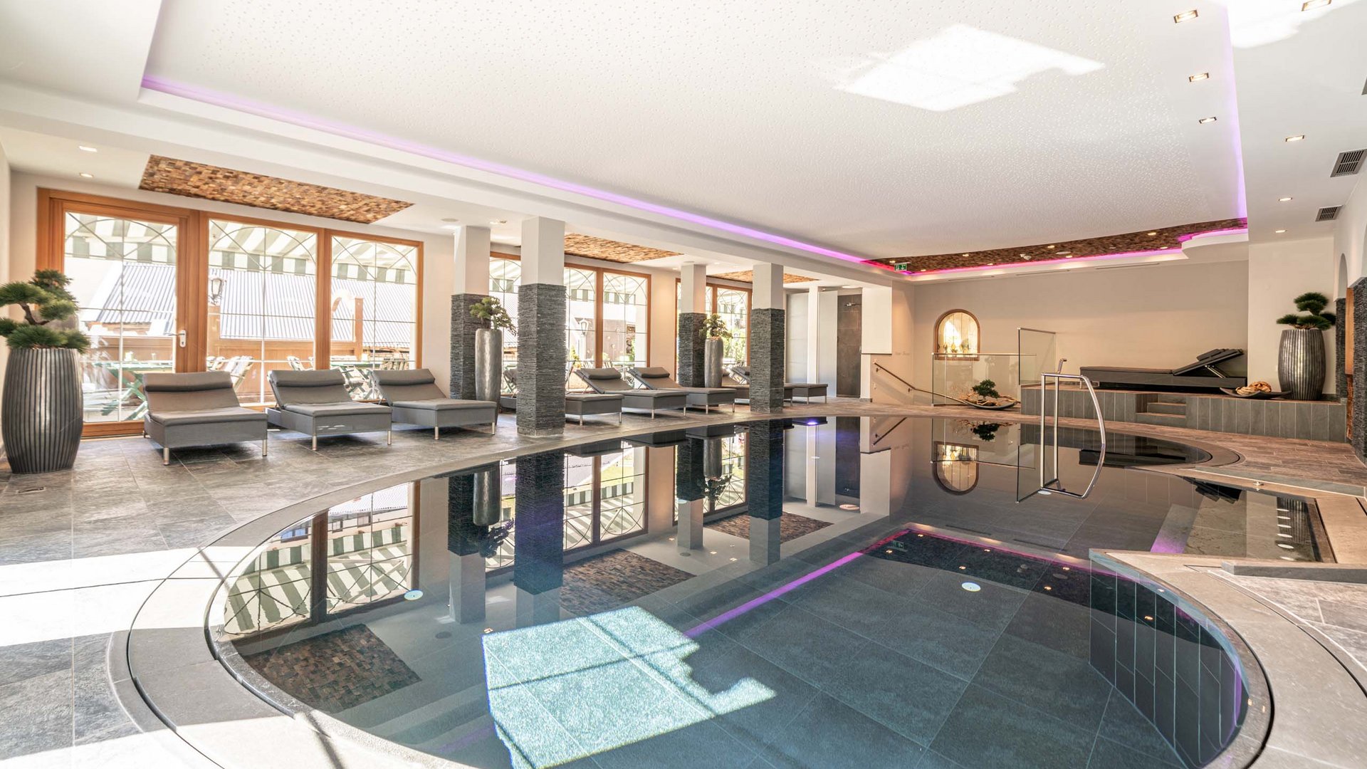 Sauna village & mountain lake: our hotel in Tyrol with pool Indoor modern swimming pool with loungers by the windows