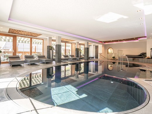 Sauna village & mountain lake: our hotel in Tyrol with pool Indoor modern swimming pool with loungers by the windows