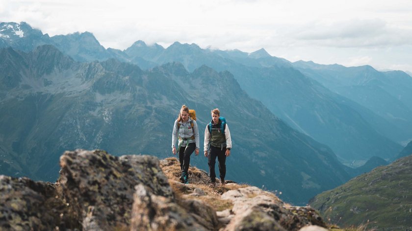 The Ötztal Trail Two hikers with backpacks walking in the mountains under cloudy sky