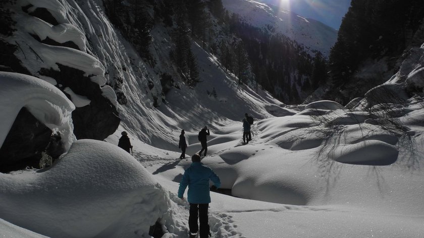 Explore winter’s beauty on foot People hiking in sunny snowy valley surrounded by trees