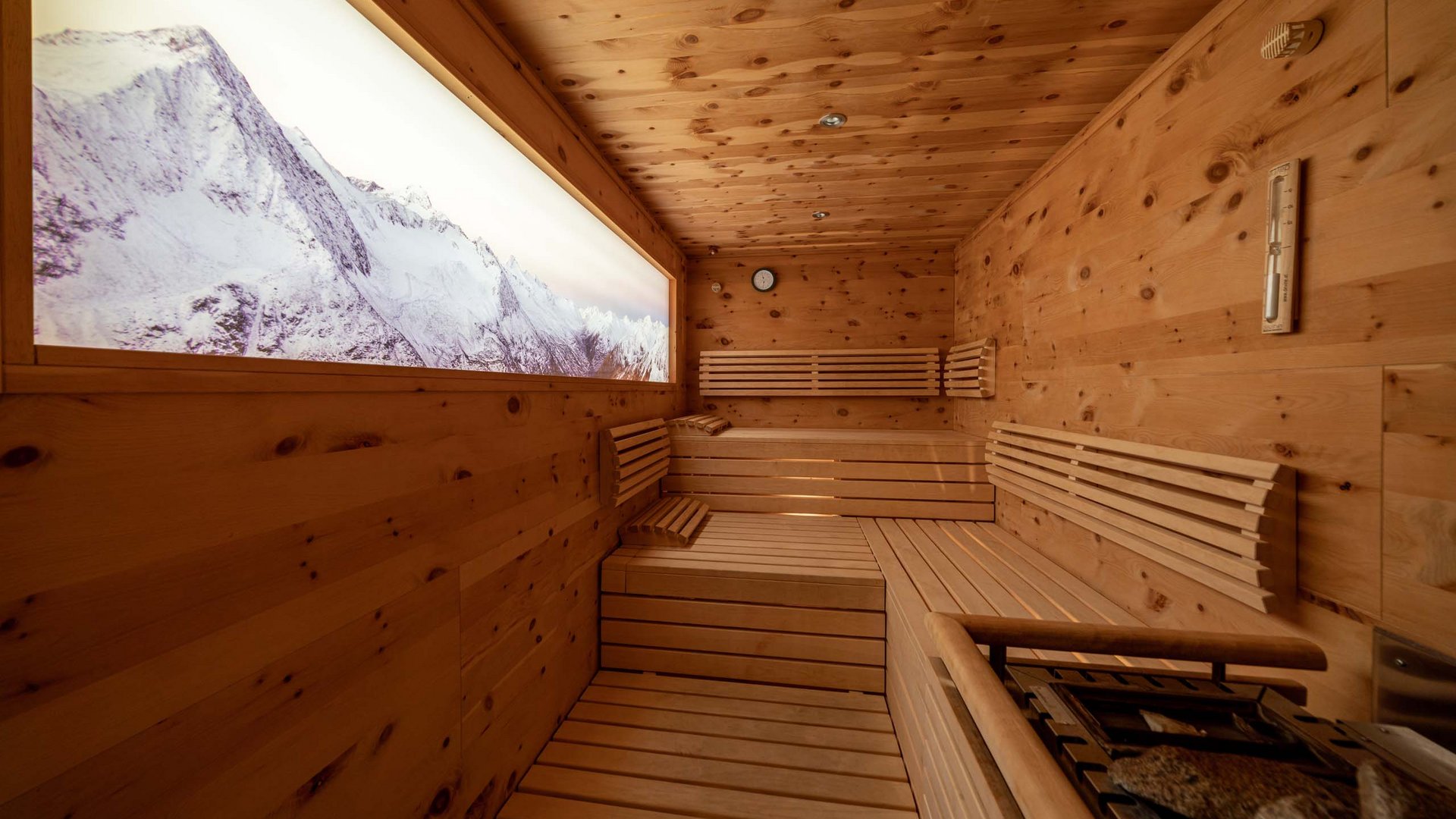 Sauna village & mountain lake: our hotel in Tyrol with pool Wooden sauna with a view of snow-covered mountains through a large window