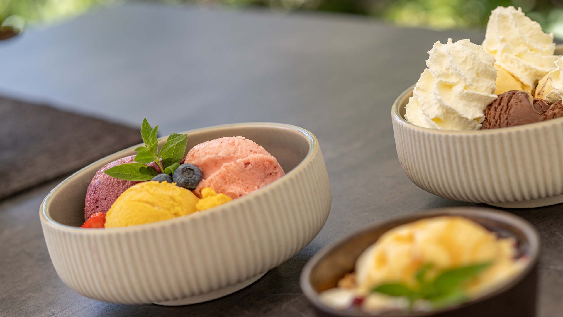 Des plaisirs naturels dans notre restaurant à Vent Bols de différentes glaces avec crème fouettée sur une table grise