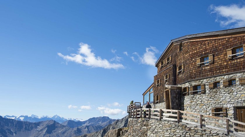 An Alpine adventure in Ötztal Wood and stone mountain hut overlooking alpine peaks under a blue sky