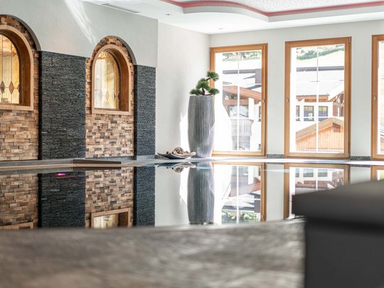 Sauna village & mountain lake: our hotel in Tyrol with pool Indoor pool with large windows and decorative wall details