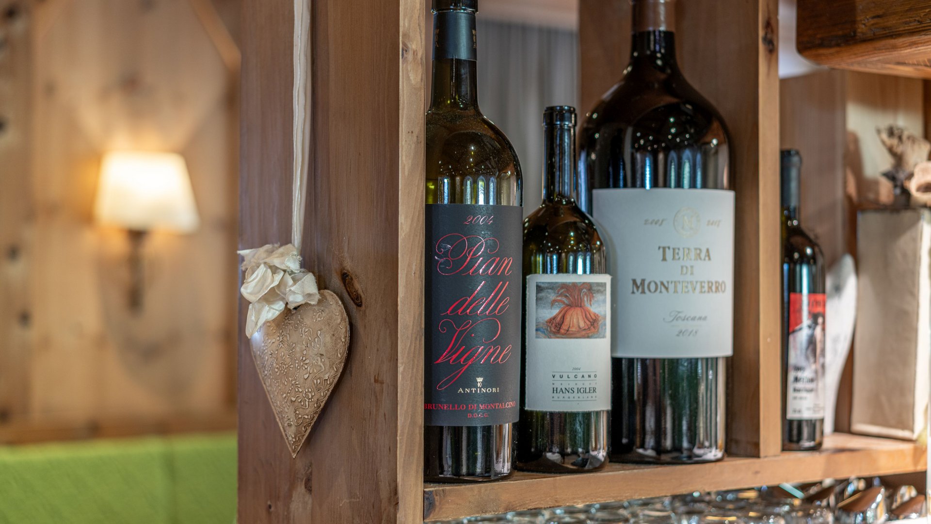 Des plaisirs naturels dans notre restaurant à Vent Différentes bouteilles de vin sur une étagère en bois rustique avec des verres en dessous