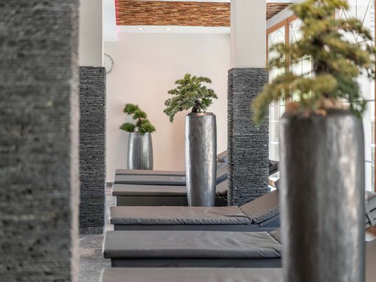Sauna village & mountain lake: our hotel in Tyrol with pool Relaxation area with gray loungers and large indoor plant pots