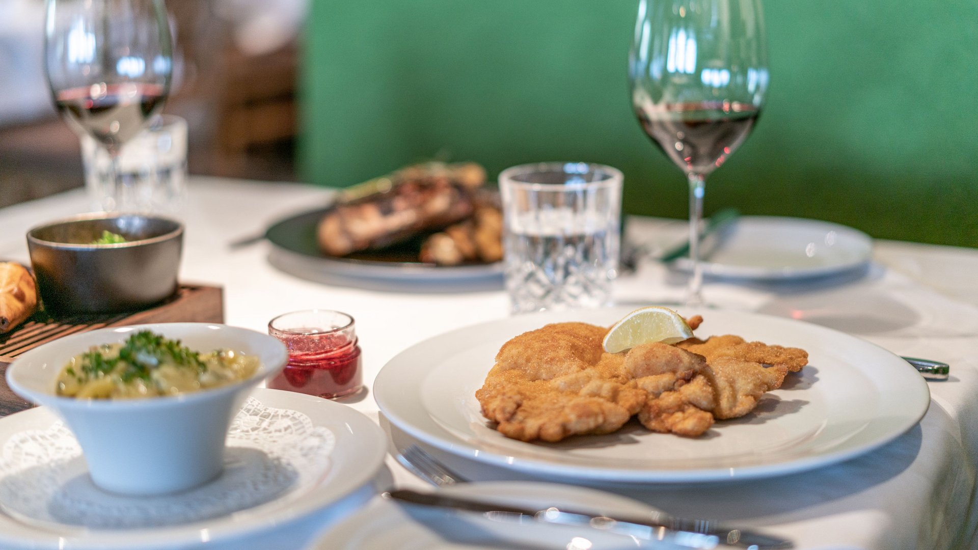 Des plaisirs naturels dans notre restaurant à Vent Table avec schnitzel viennois, sauce aux airelles, salade de pommes de terre et vin rouge au restaurant