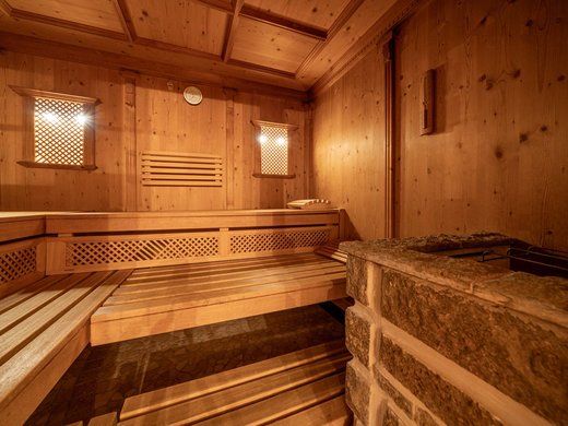 Sauna village & mountain lake: our hotel in Tyrol with pool Interior of a wooden sauna with benches and stone stove