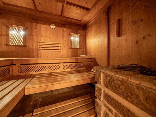 Sauna village & mountain lake: our hotel in Tyrol with pool Interior of a wooden sauna with benches and stone stove