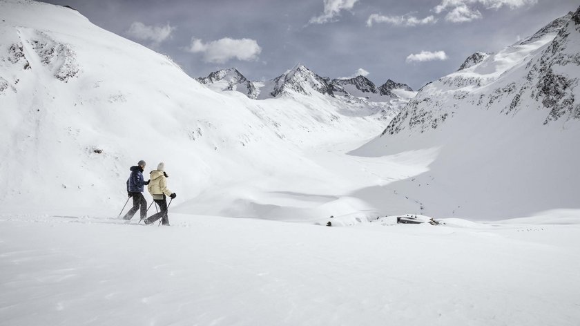 Winter hiking tip Two people snowshoeing in a snowy mountain landscape